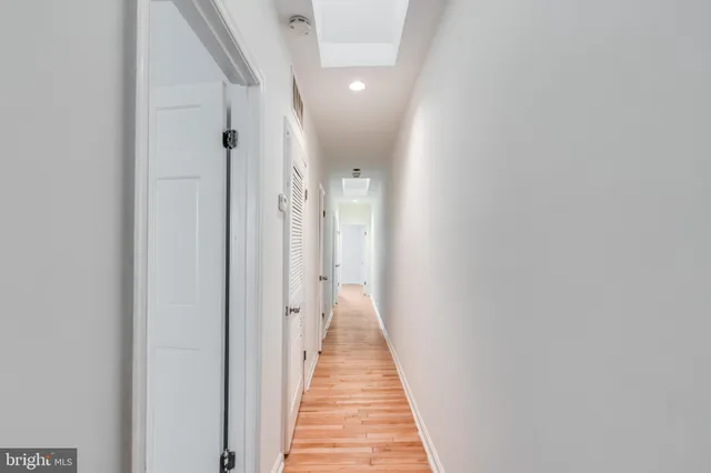 a view of a hallway with wooden floor and a bathroom