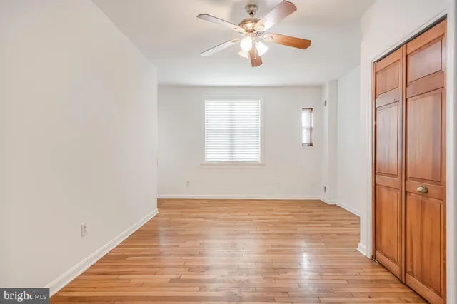 an empty room with wooden floor chandelier fan and windows