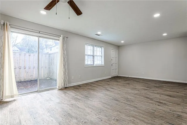 an empty room with chandelier fan and windows