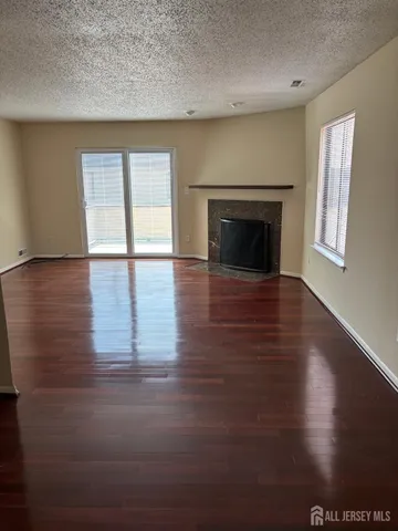 an empty room with wooden floor fireplace and windows