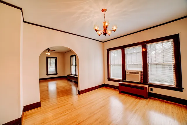 a view of an empty room with window and wooden floor