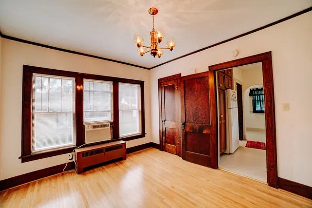 a dining room with chandelier fan and wooden floor