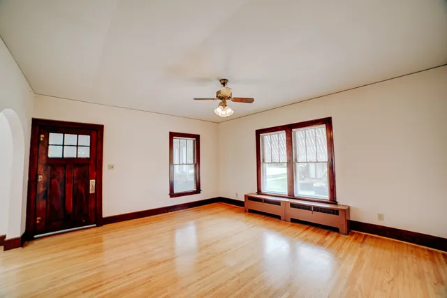 an empty room with wooden floor and windows