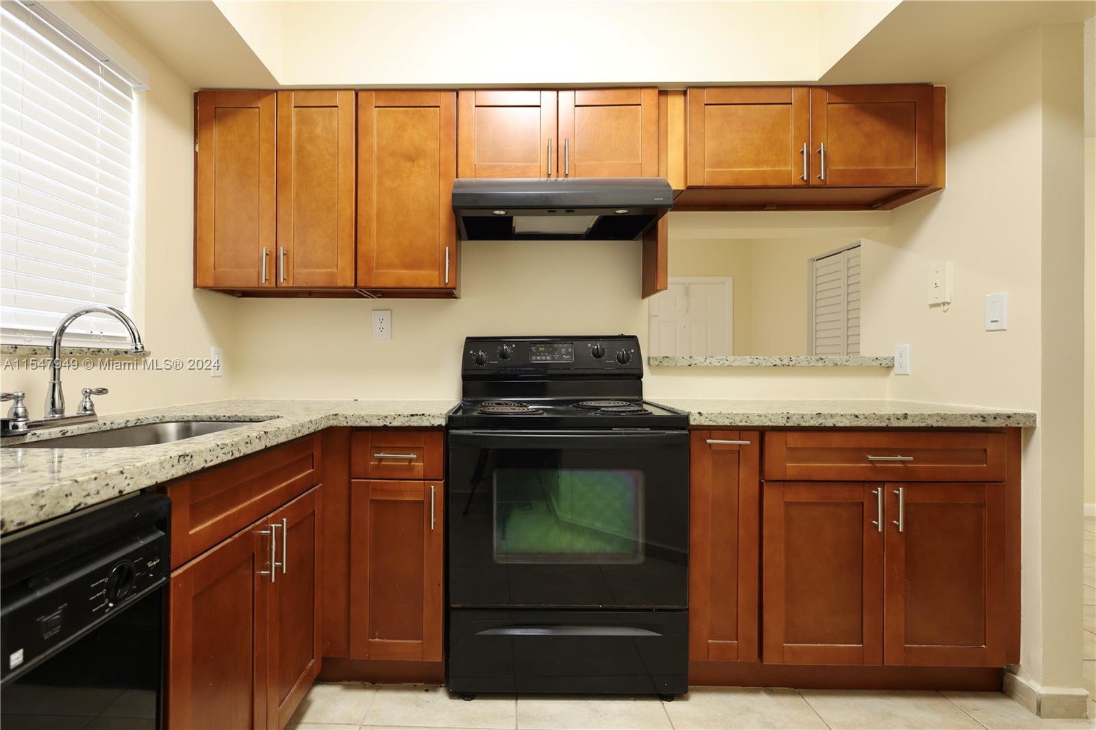 a kitchen with granite countertop wood cabinets and a stove top oven