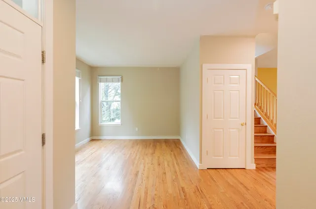 a view of an empty room with wooden floor and a window