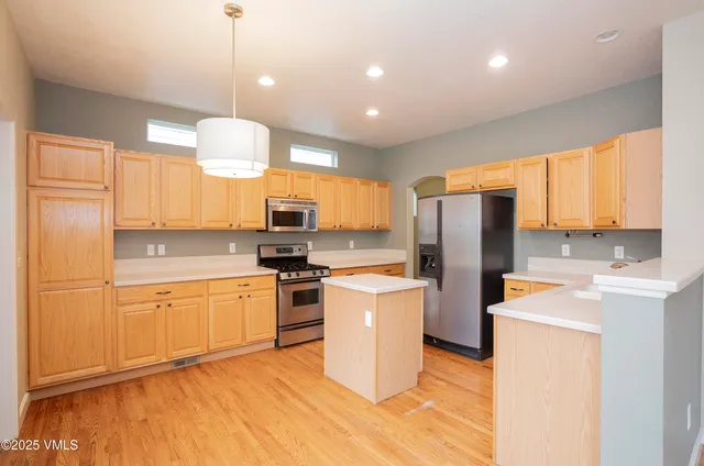 a kitchen with stainless steel appliances granite countertop a refrigerator a stove top oven a sink dishwasher and white cabinets with wooden floor