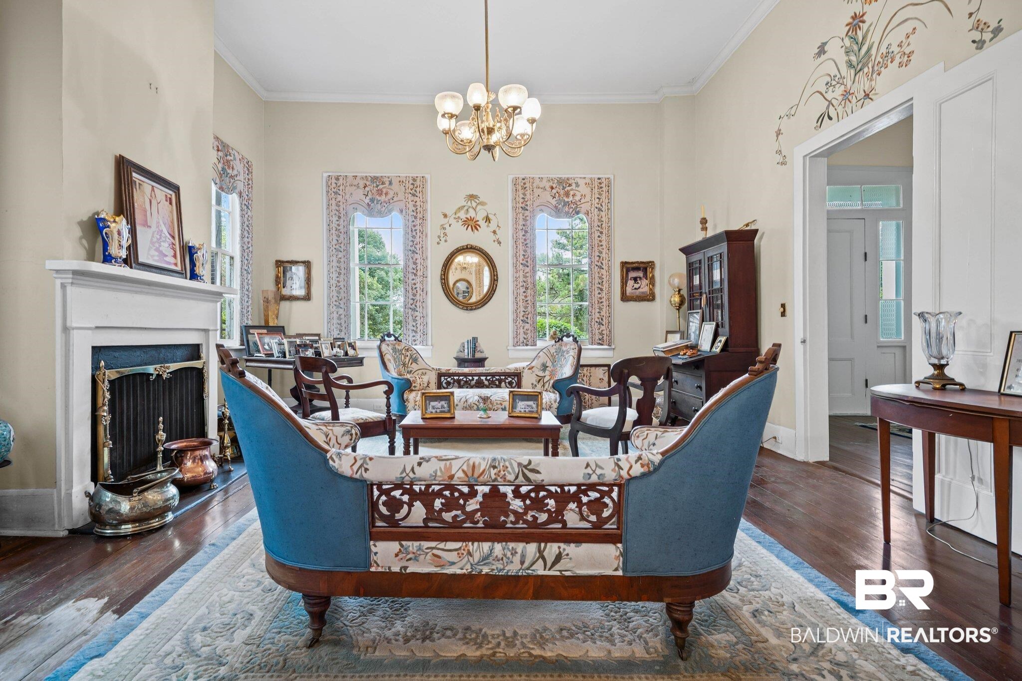 23561 Main Street Fairhope, AL 36532 - Photo 12 of 45 Living room with hardwood / wood-style flooring, a chandelier, a fireplace with raised hearth, and crown molding