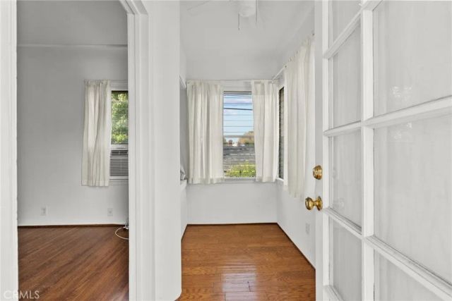a view of hallway with window and wooden floor