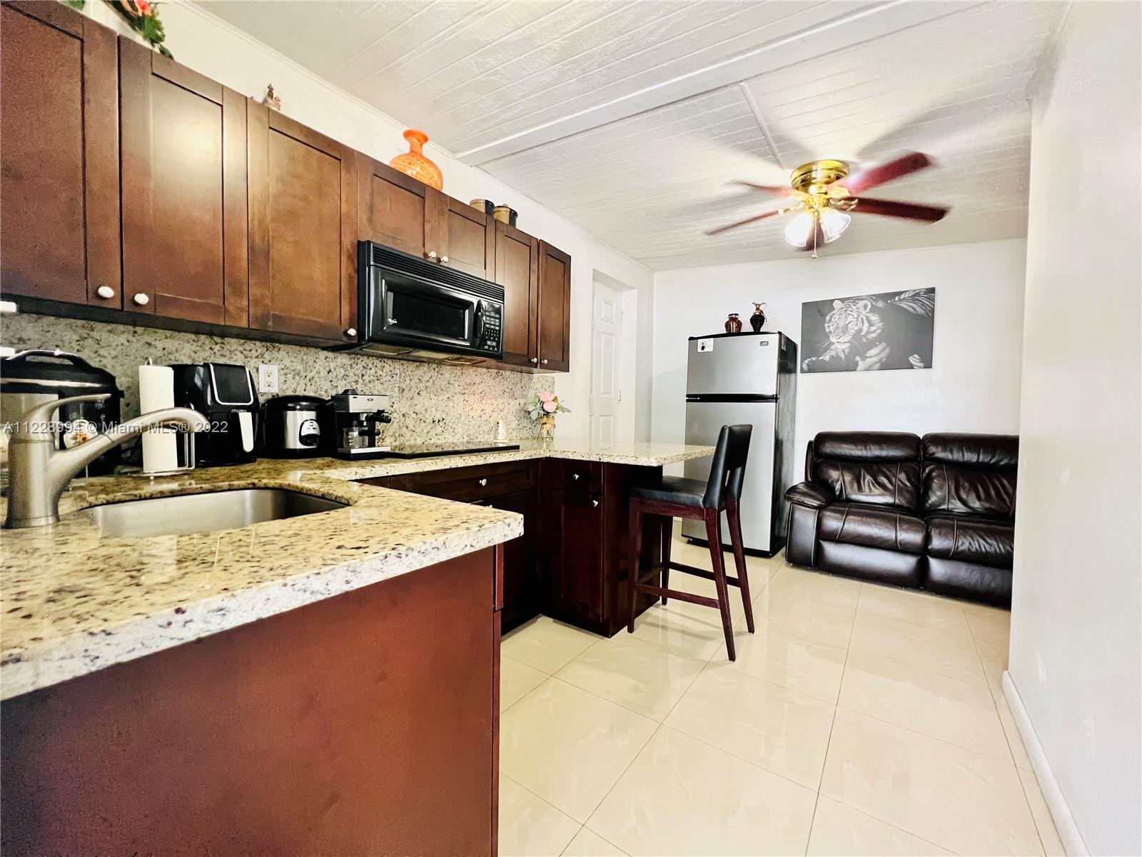 599 West 46th Place Hialeah, FL 33012 - Photo 15 of 25 a kitchen with stainless steel appliances granite countertop a sink dishwasher a stove a microwave oven with a dining table and chairs