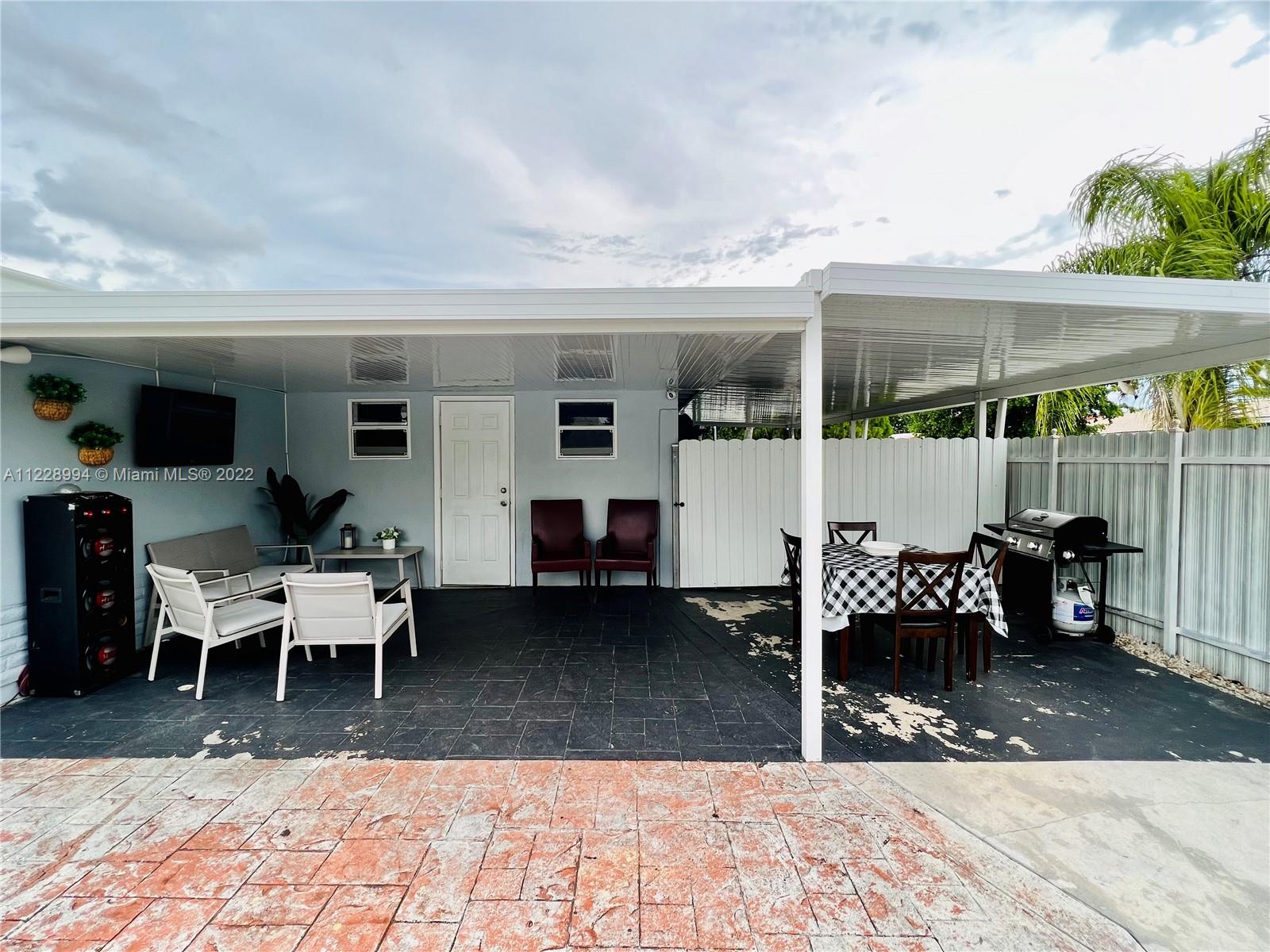 599 West 46th Place Hialeah, FL 33012 - Photo 17 of 25 a view of a patio with table and chairs with wooden fence