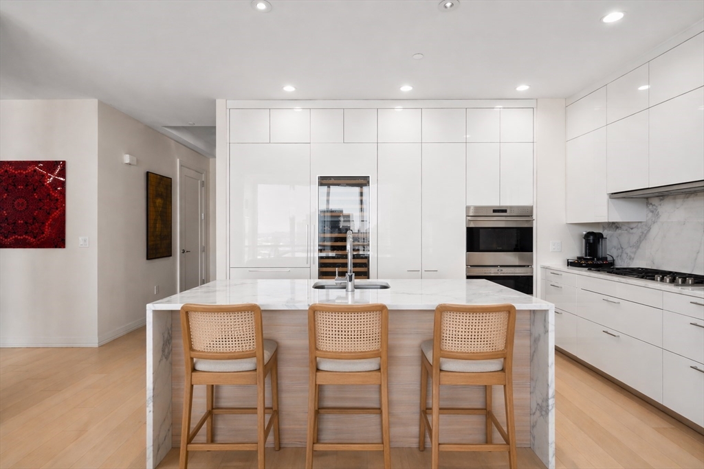 1 Franklin Street, Unit 4704 Boston, MA 02110 - Photo 7 of 33 a kitchen with kitchen island cabinets and chairs in it