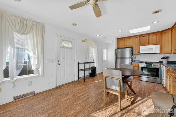 a kitchen with stainless steel appliances a stove a refrigerator and a dining table with wooden floor