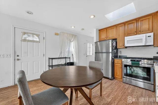 a kitchen with stainless steel appliances granite countertop a refrigerator a stove a microwave oven with a dining table and chairs