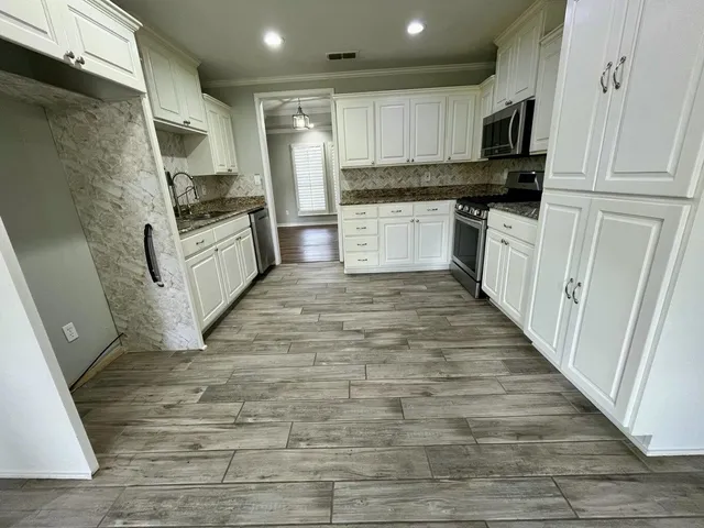 a kitchen with granite countertop a refrigerator stove top oven and sink