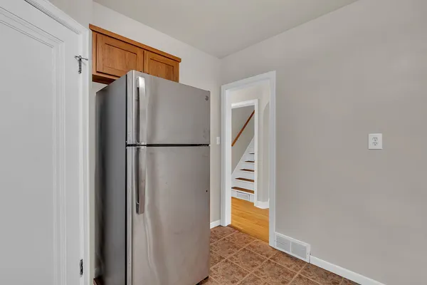 a view of hallway with wooden floor and a refrigerator
