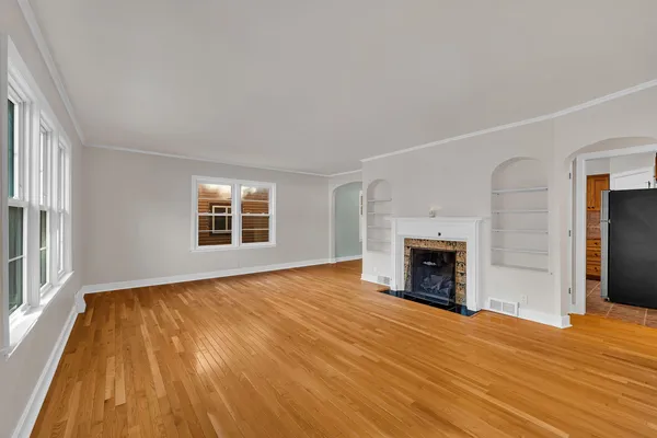 wooden floor fireplace and windows in an empty room