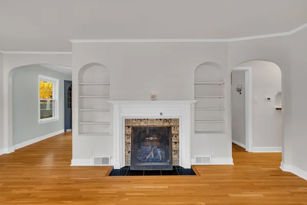 an empty room with wooden floor fireplace and windows