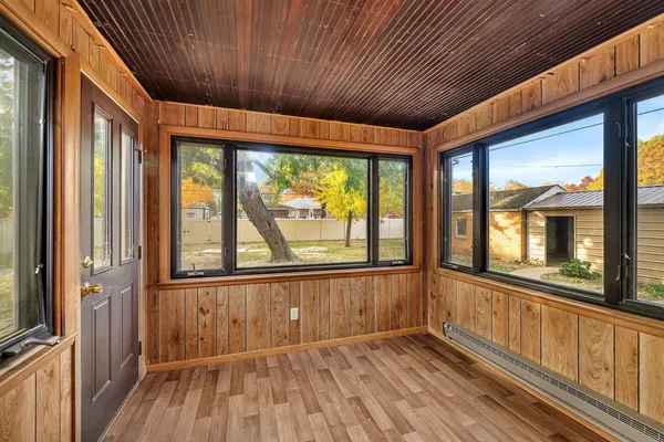 a view of an empty room with wooden floor and a window