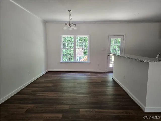 an empty room with wooden floor chandelier and windows