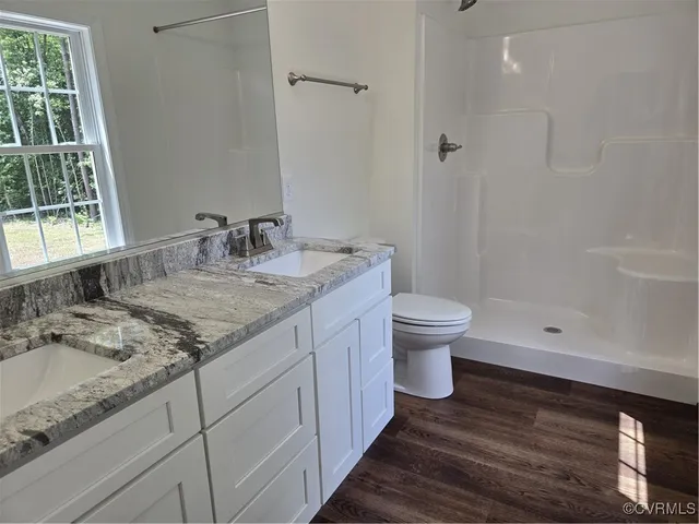 a bathroom with a granite countertop sink a toilet and shower