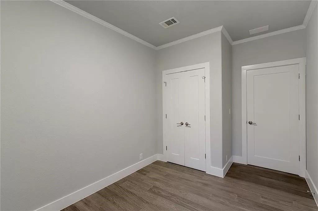 1217 Eleanor Street Austin, TX 78721 - Photo 14 of 17 Unfurnished bedroom with ornamental molding, dark wood-type flooring, and a closet