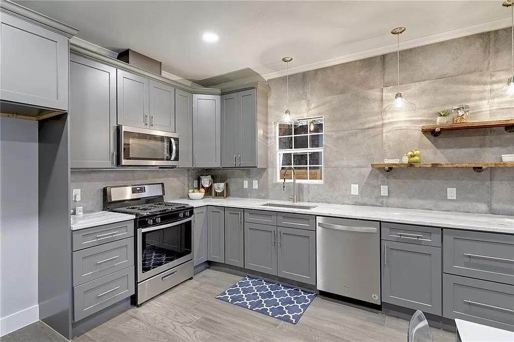 1217 Eleanor Street Austin, TX 78721 - Photo 7 of 17 Kitchen with gray cabinets, stainless steel appliances, light wood finished floors, light stone countertops, and backsplash