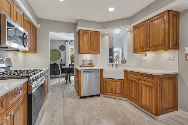 a kitchen with stainless steel appliances granite countertop wooden cabinets a sink a stove a refrigerator and island with wooden floor