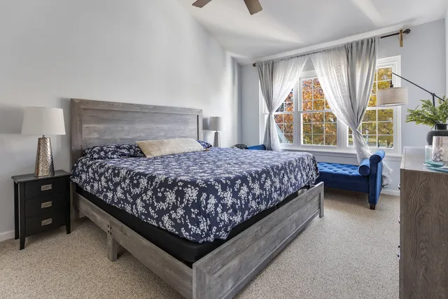 a bedroom with a bed lamp and a large window