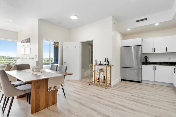 a kitchen with stainless steel appliances refrigerator wooden floor dining table and chairs