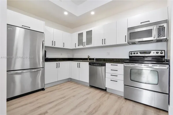 a kitchen with white cabinets stainless steel appliances and wooden floor
