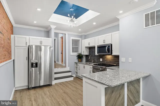 a kitchen with stainless steel appliances granite countertop a refrigerator oven a stove a dining table and chairs with wooden floor