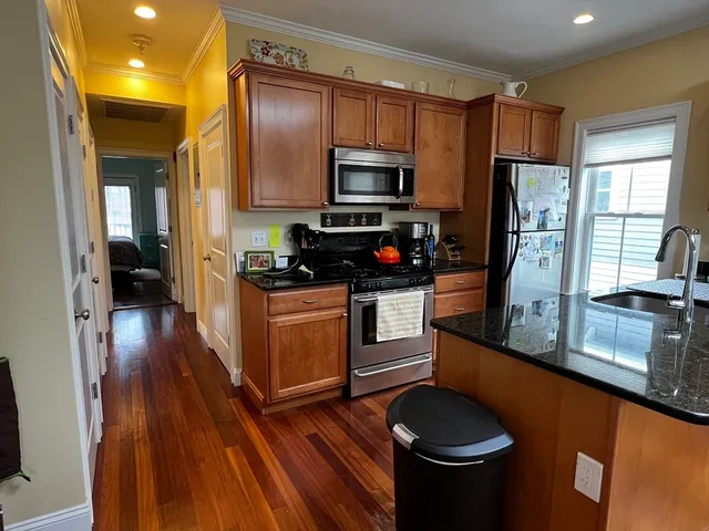 a kitchen with stainless steel appliances a stove a sink dishwasher a refrigerator and a stove with wooden floor