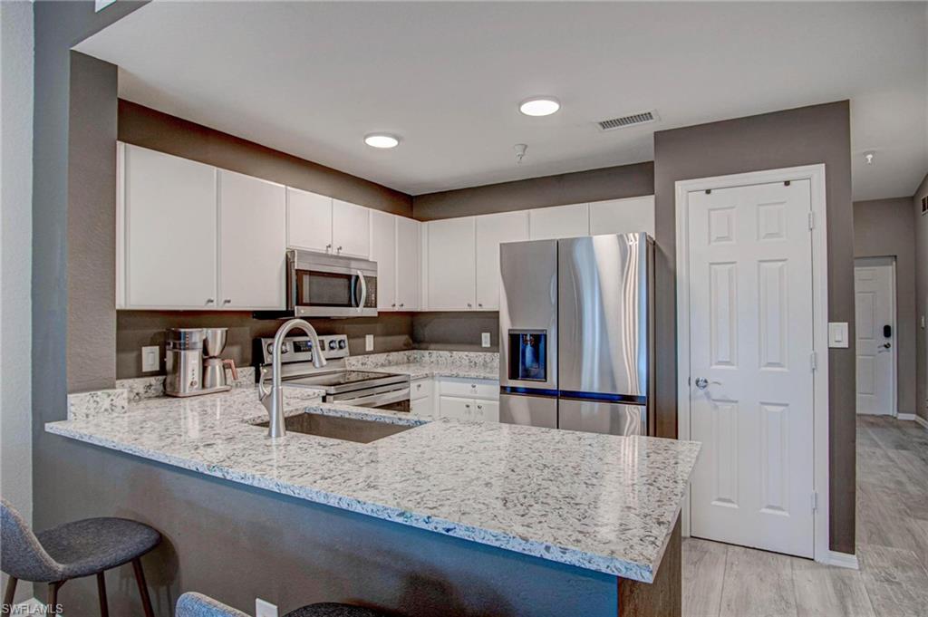 4450 Botanical Pl Circle, Unit 406 Naples, FL 34112 - Photo 15 of 16 a kitchen with stainless steel appliances granite countertop a refrigerator sink and stove
