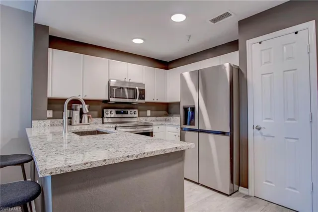 a kitchen with granite countertop a refrigerator and a stove top oven