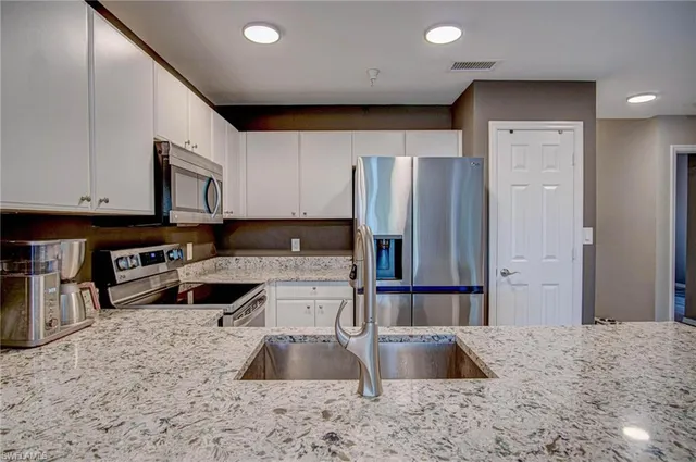 a kitchen with stainless steel appliances granite countertop a refrigerator a stove and a sink with wooden floor