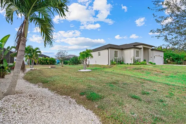 a view of a house with a big yard and palm trees