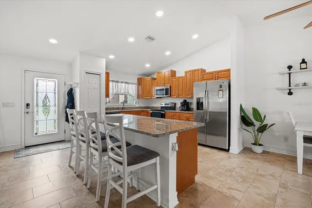 a kitchen with stainless steel appliances granite countertop a table and chairs