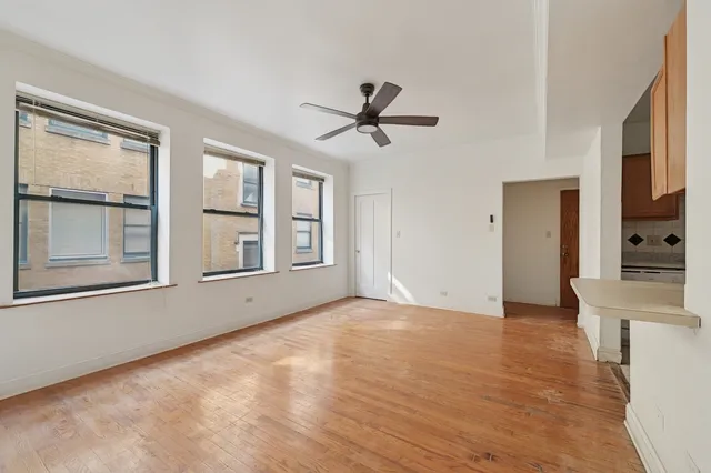 a view of an empty room with a window and wooden floor