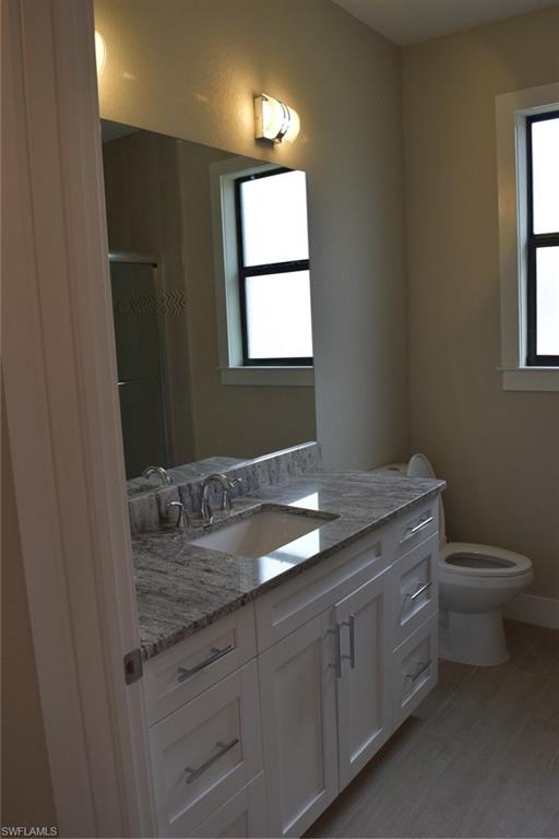 9045 Aster Road Fort Myers, FL 33967 - Photo 16 of 23 a bathroom with a granite countertop toilet sink and window