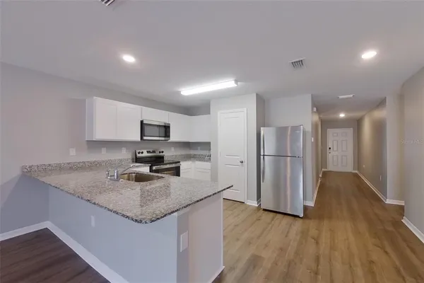 a kitchen with stainless steel appliances granite countertop a sink refrigerator and cabinets