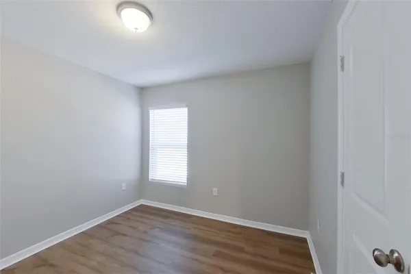 an empty room with wooden floor and window