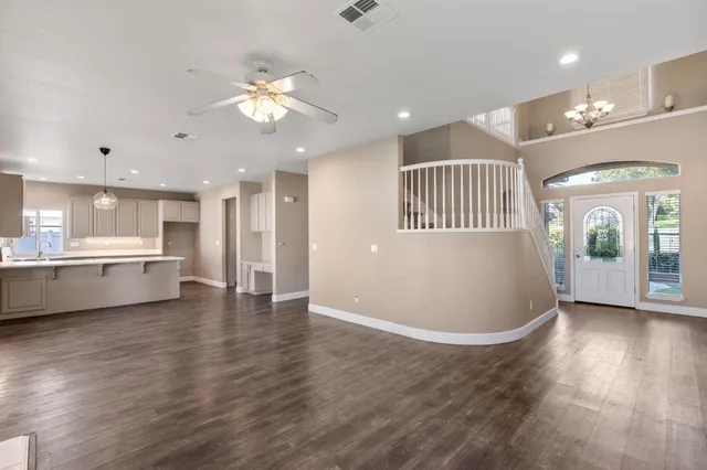 a view of an empty room and kitchen with a ceiling fan