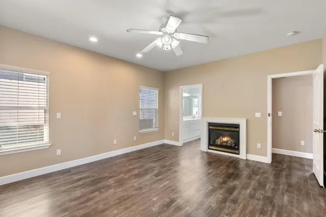 an empty room with wooden floor fireplace and window