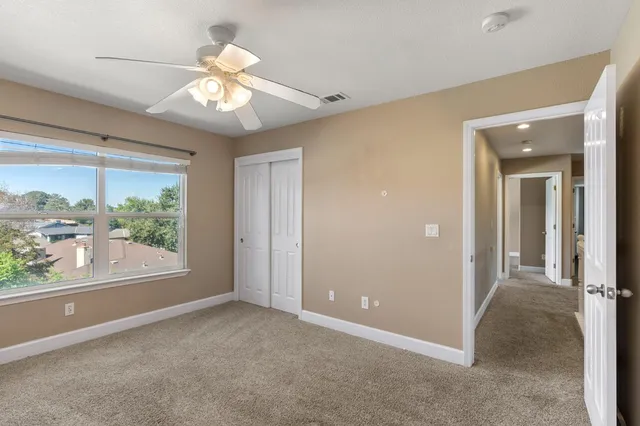 an empty room with windows and chandelier fan