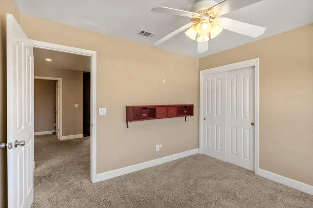 an empty room with windows and ceiling fan