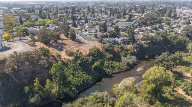 an aerial view of residential houses with outdoor space and trees