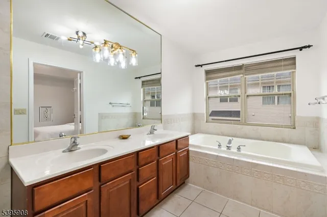a bathroom with a tub a sink double vanity and a mirror