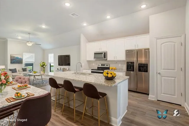 a large kitchen with stainless steel appliances granite countertop a lot of counter space and wooden floors