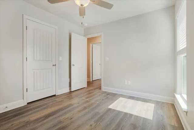 an empty room with wooden floor fan and window