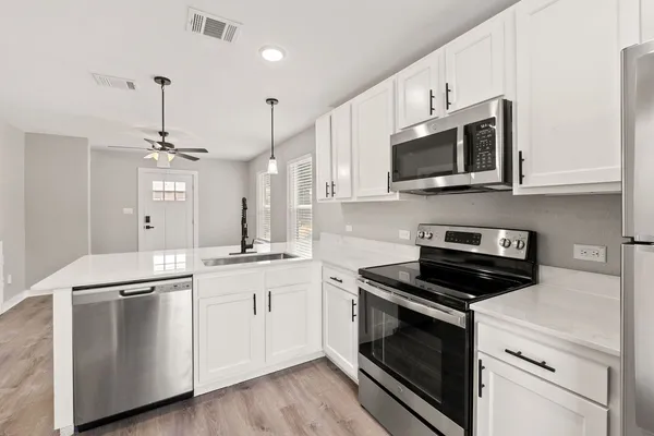 a kitchen with stainless steel appliances white cabinets and a stove top oven